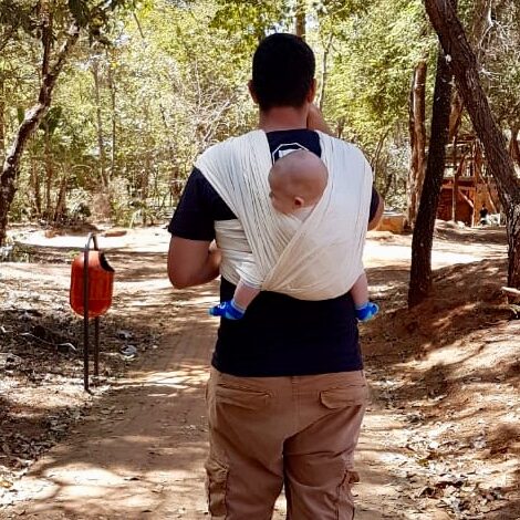 Pai carregando o bebê no sling durante passeio do grupo em meio à natureza