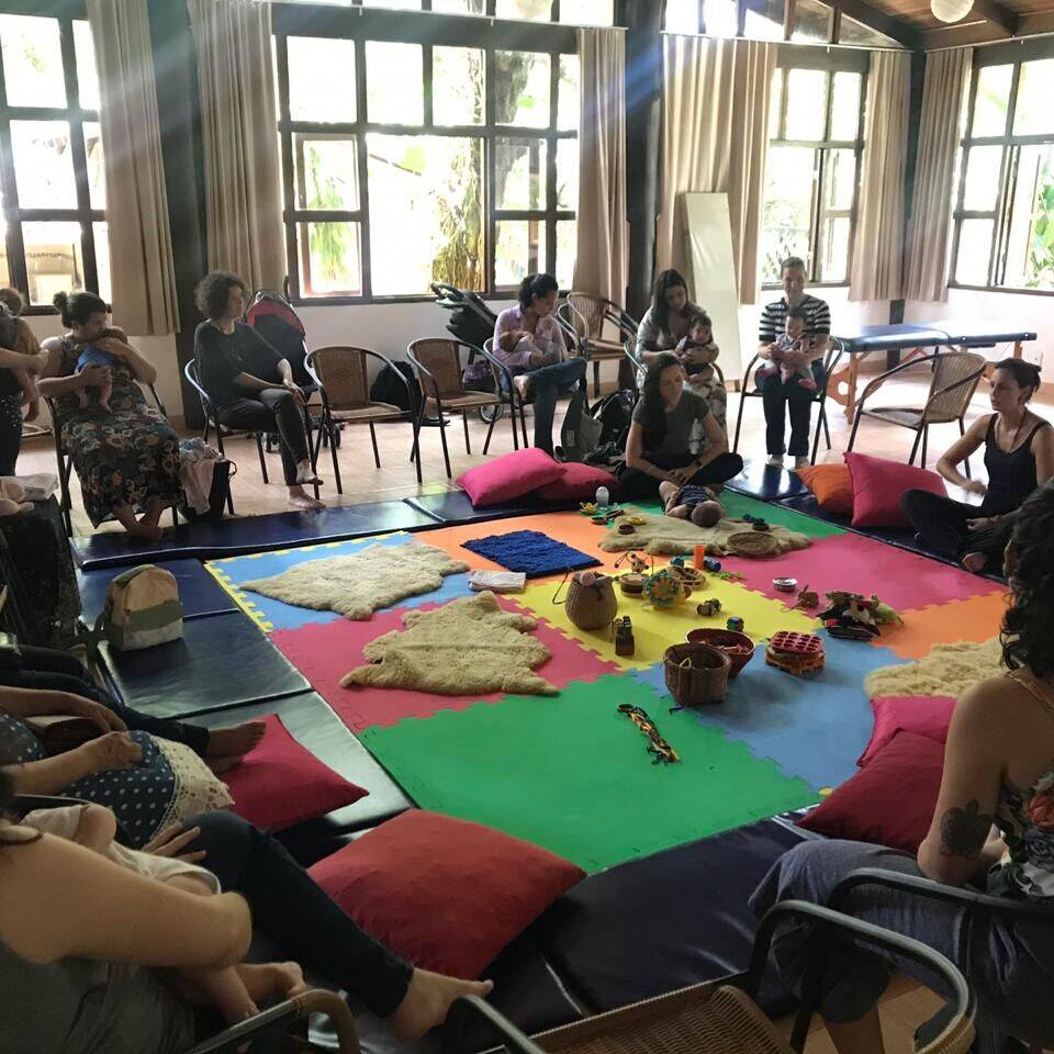 Roda de mães e bebês em um salão iluminado durante encontro do Parental Lab