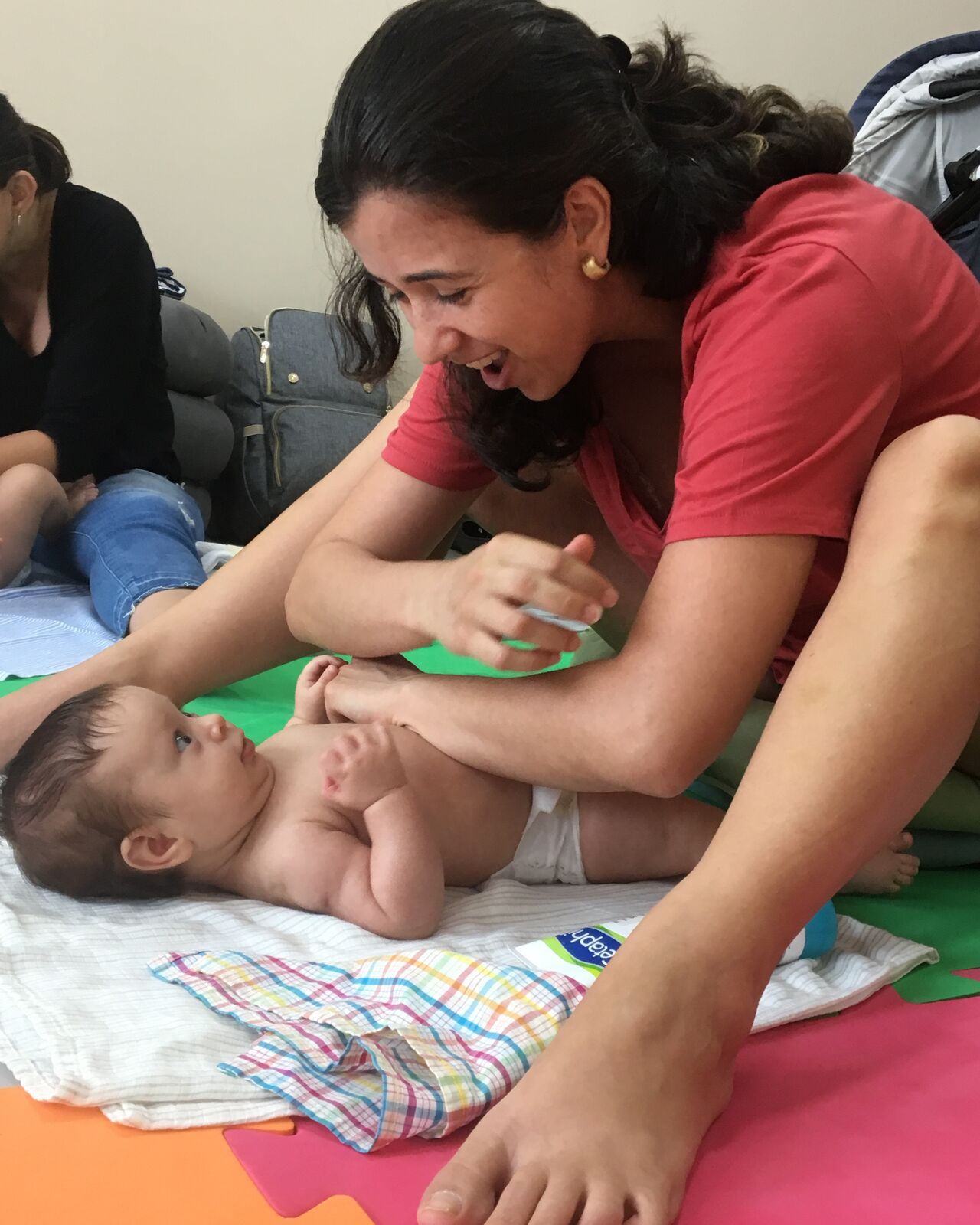 Luciana Lima conduzindo massagem shantala com um bebê durante encontro